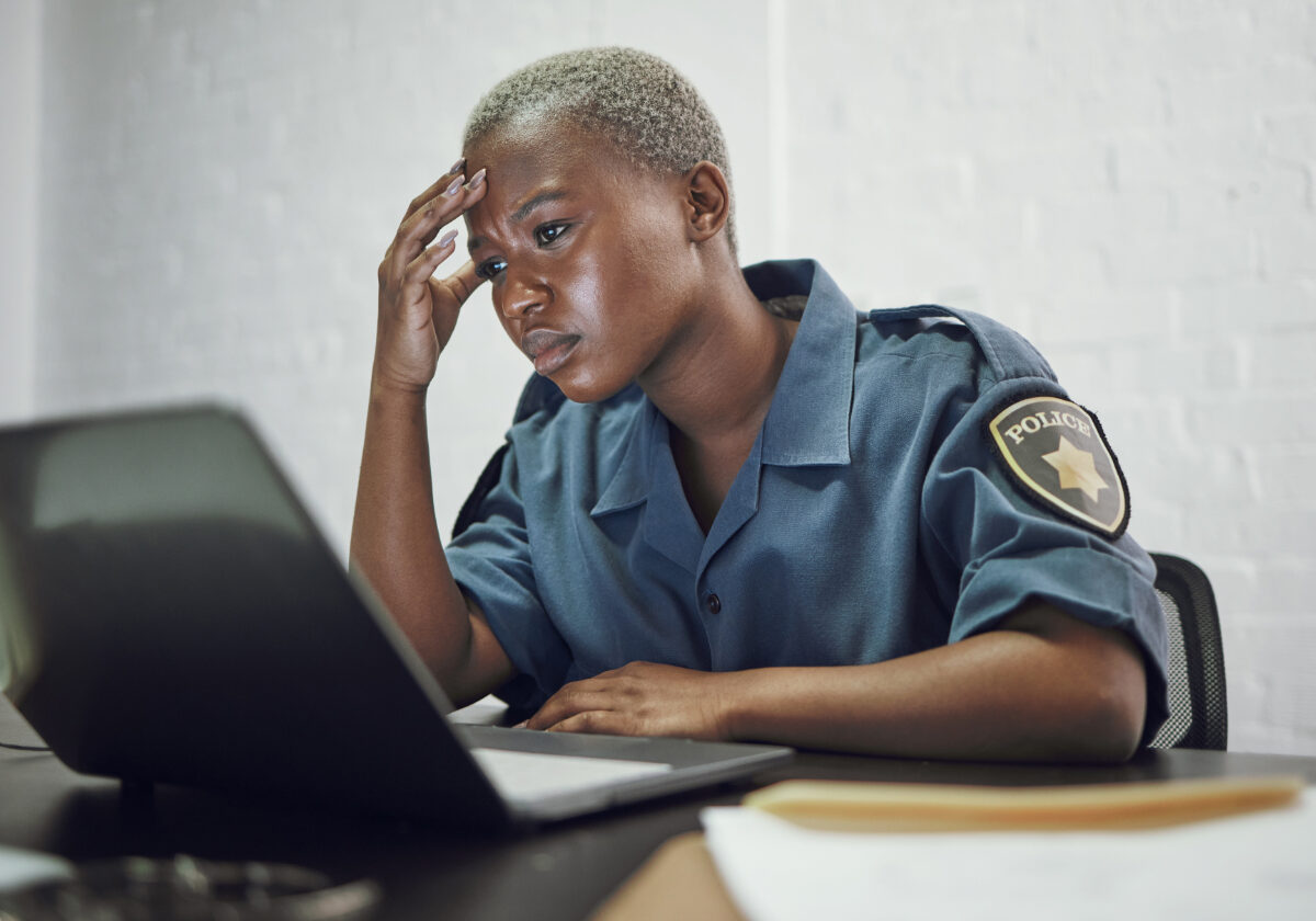 Police, woman and headache from working with stress on computer or frustrated with case, report or anxiety in security. African, officer and tired from work on documents in office or station.